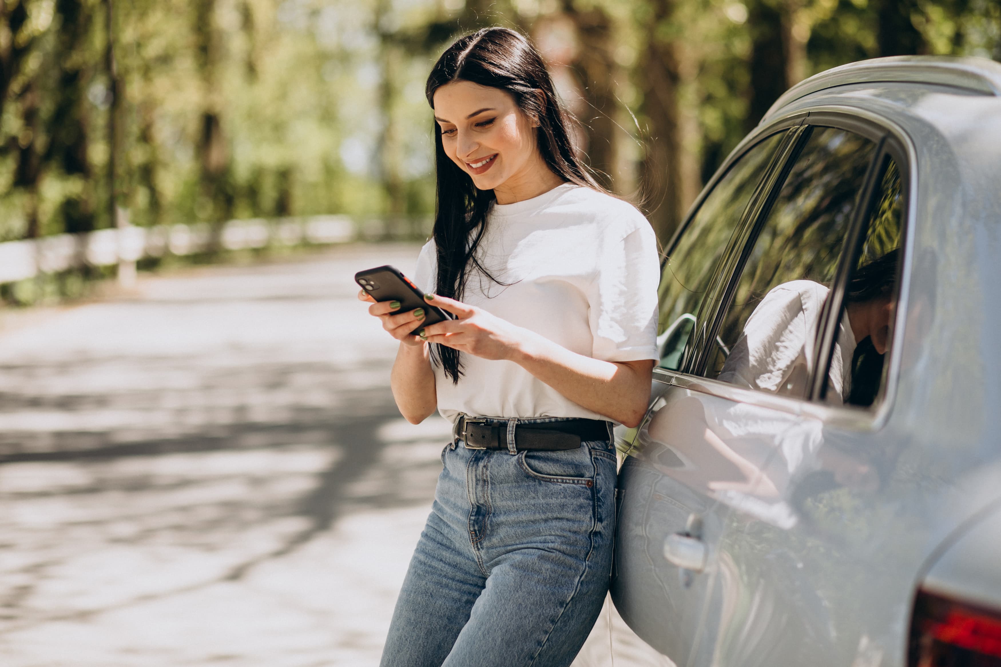 Mulher conversando ao celular ao lado do carro elétrico