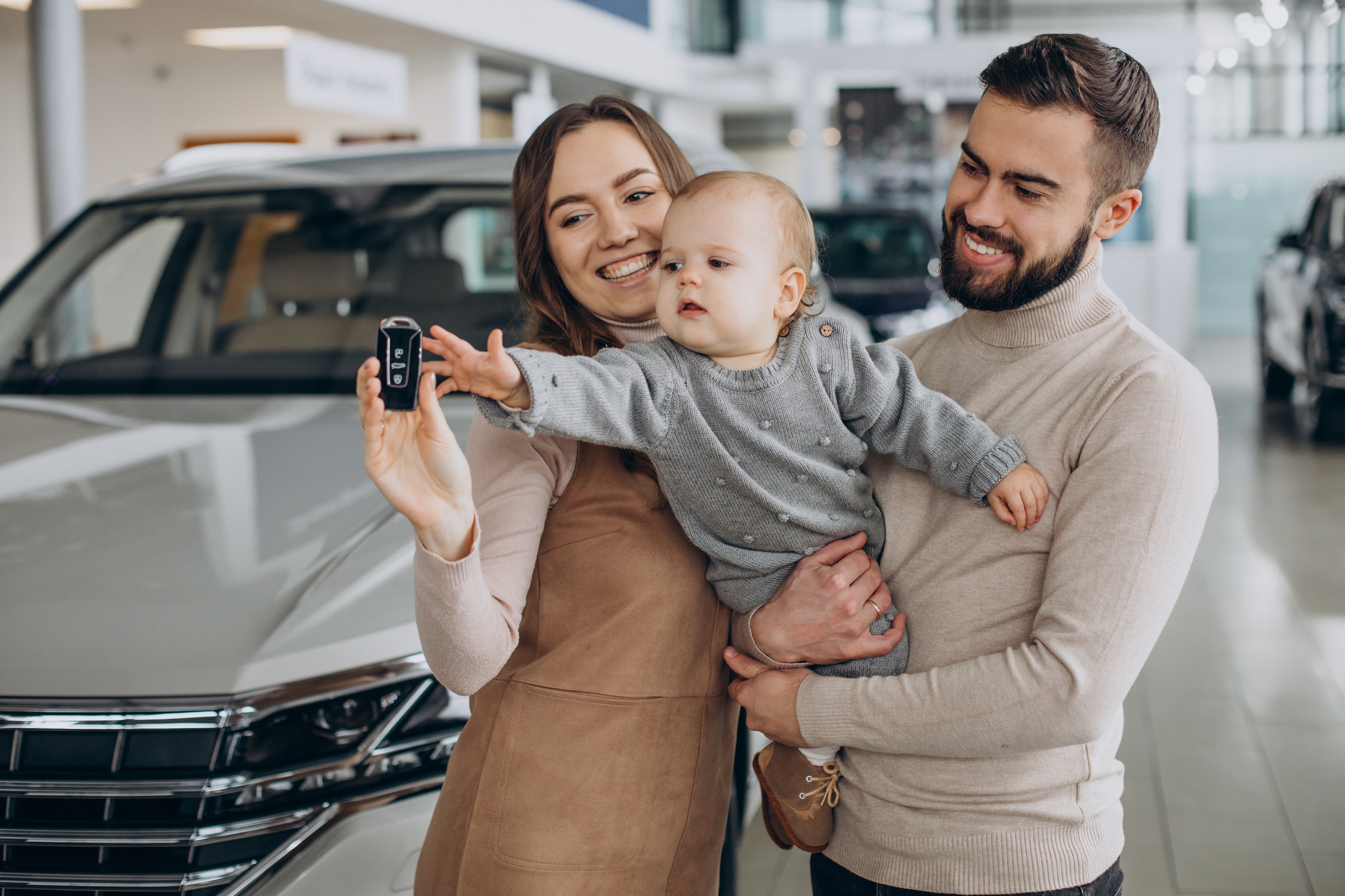 Família com bebê escolhendo carro na concessionária