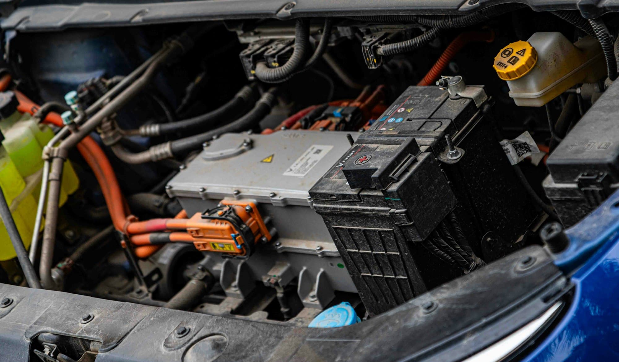 Compartimento do motor de um carro elétrico com cabos de alta tensão alaranjados à mostra