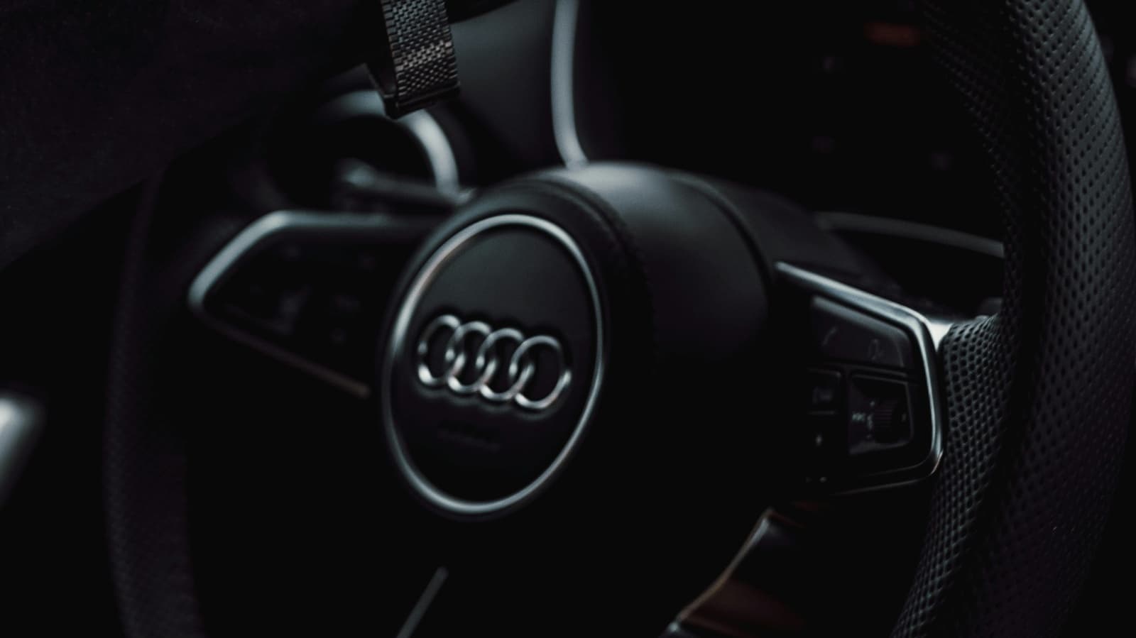 Volante de um carro Audi visto de perto, com o logotipo da marca em destaque no centro