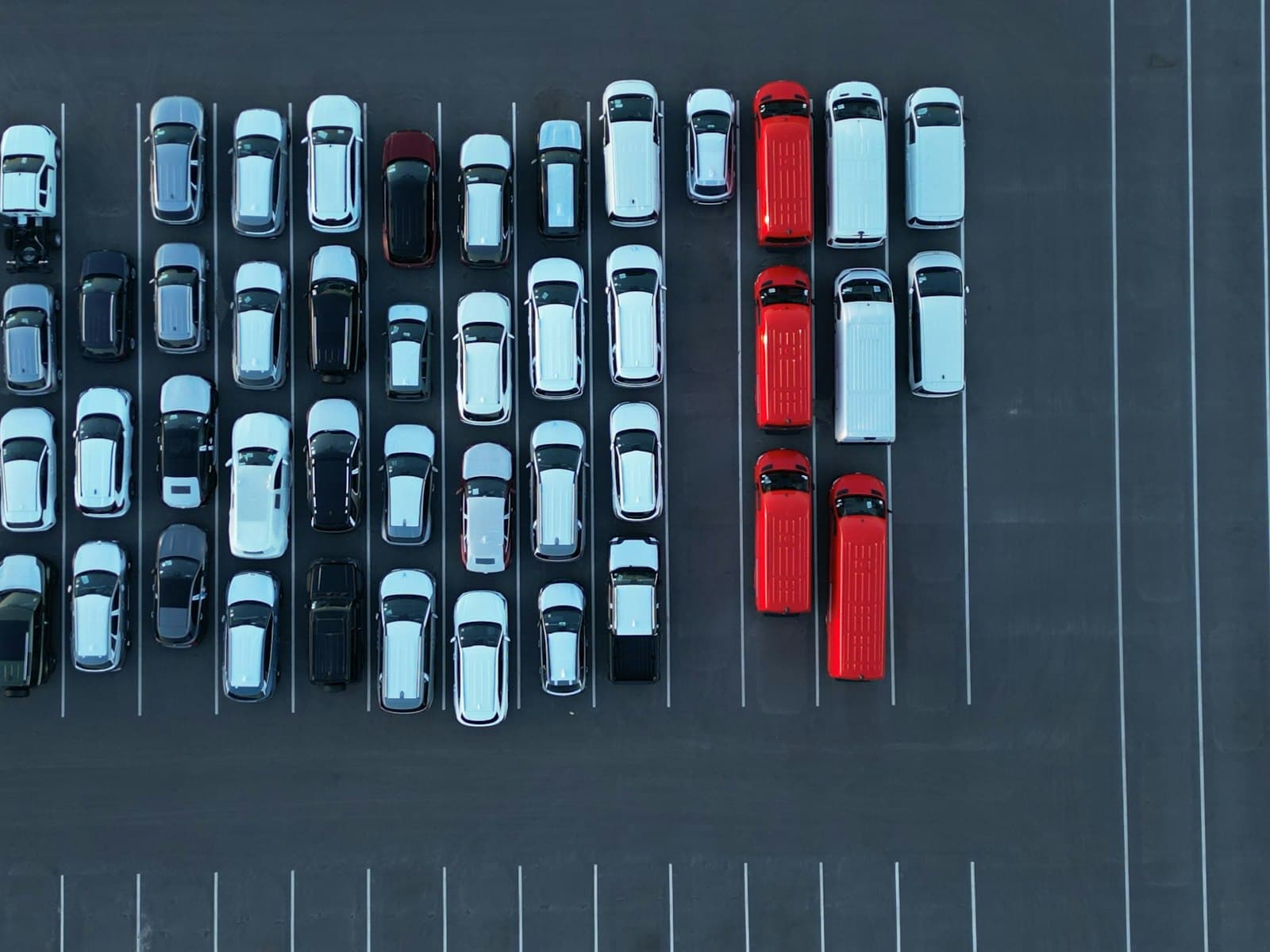 Vista aérea de um pátio com dezenas de carros novos estacionados em fileiras